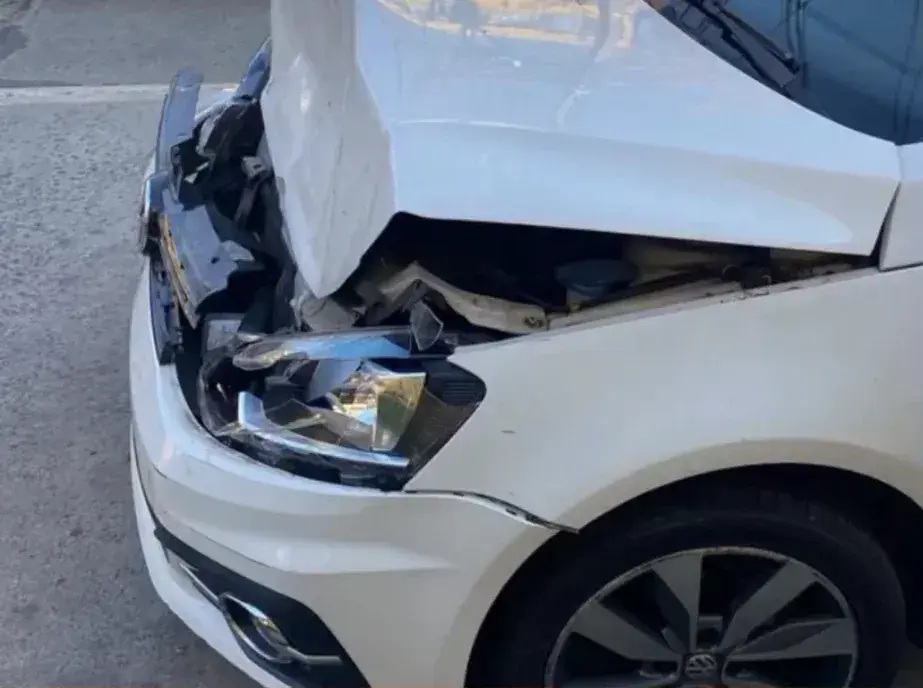 Antes: Volkswagen blanco con el frente chocado, capó doblado y foco roto