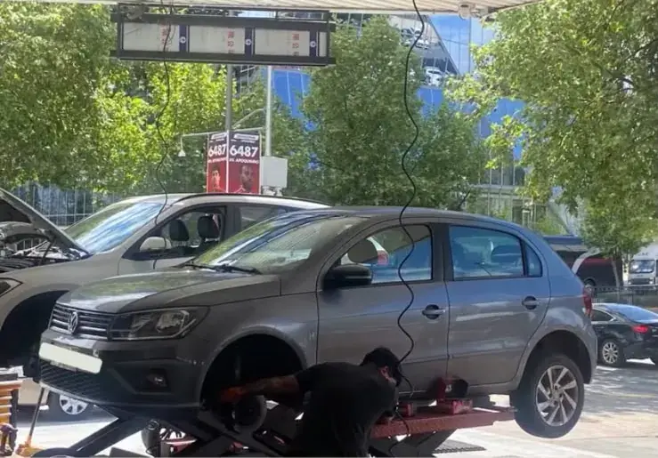 Volkswagen sobre un elevador mientras un técnico trabaja en la rueda delantera
