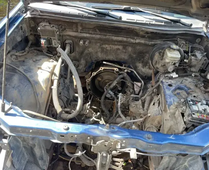 Compartimento del motor de una camioneta azul, con la transmisión a la vista